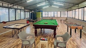 Amplia zona recreativa interior con mesa de billar, mesa de futbolín y mesa de snooker.