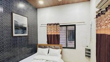 A bedroom with a bed, a ceiling fan, a window with curtains, and a wall-mounted air conditioning unit.