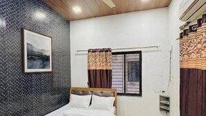 Un dormitorio con cama, ventilador de techo, ventana con cortinas y aire acondicionado instalado en la pared.