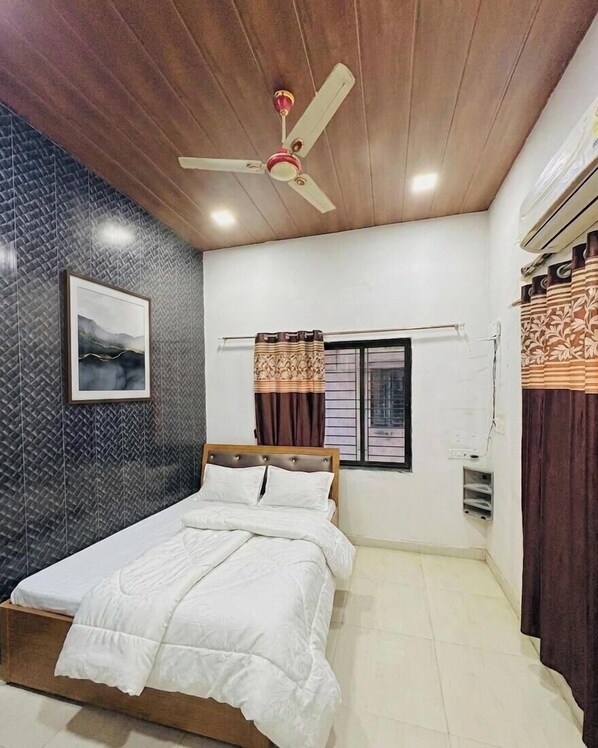 A bedroom with a bed, a ceiling fan, a window with curtains, and a wall-mounted air conditioning unit.