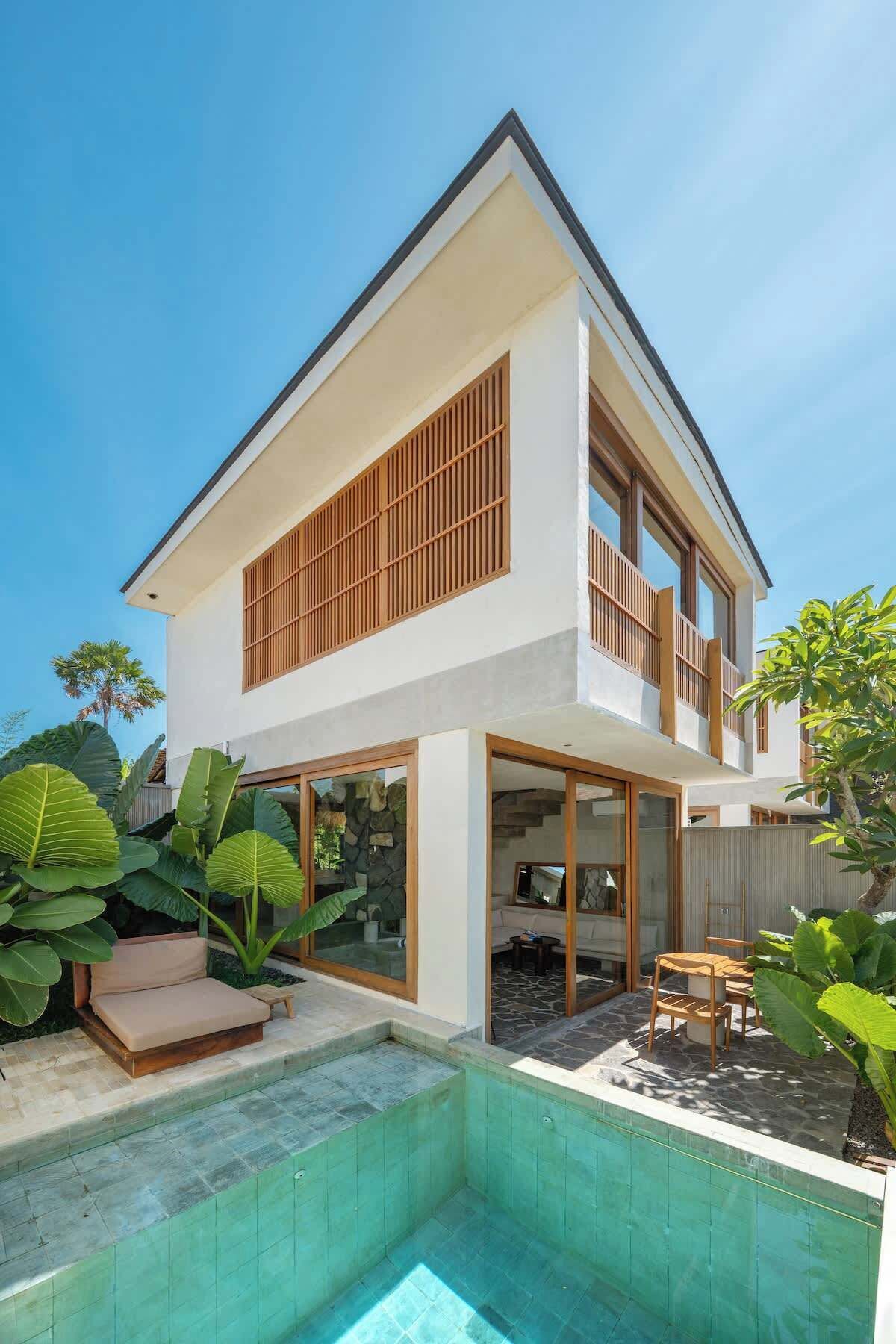 A modern two-story house with a swimming pool, large windows, and a balcony.