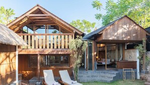 Una casa de madera con balcón, piscina y un edificio aparte con fachada de piedra.