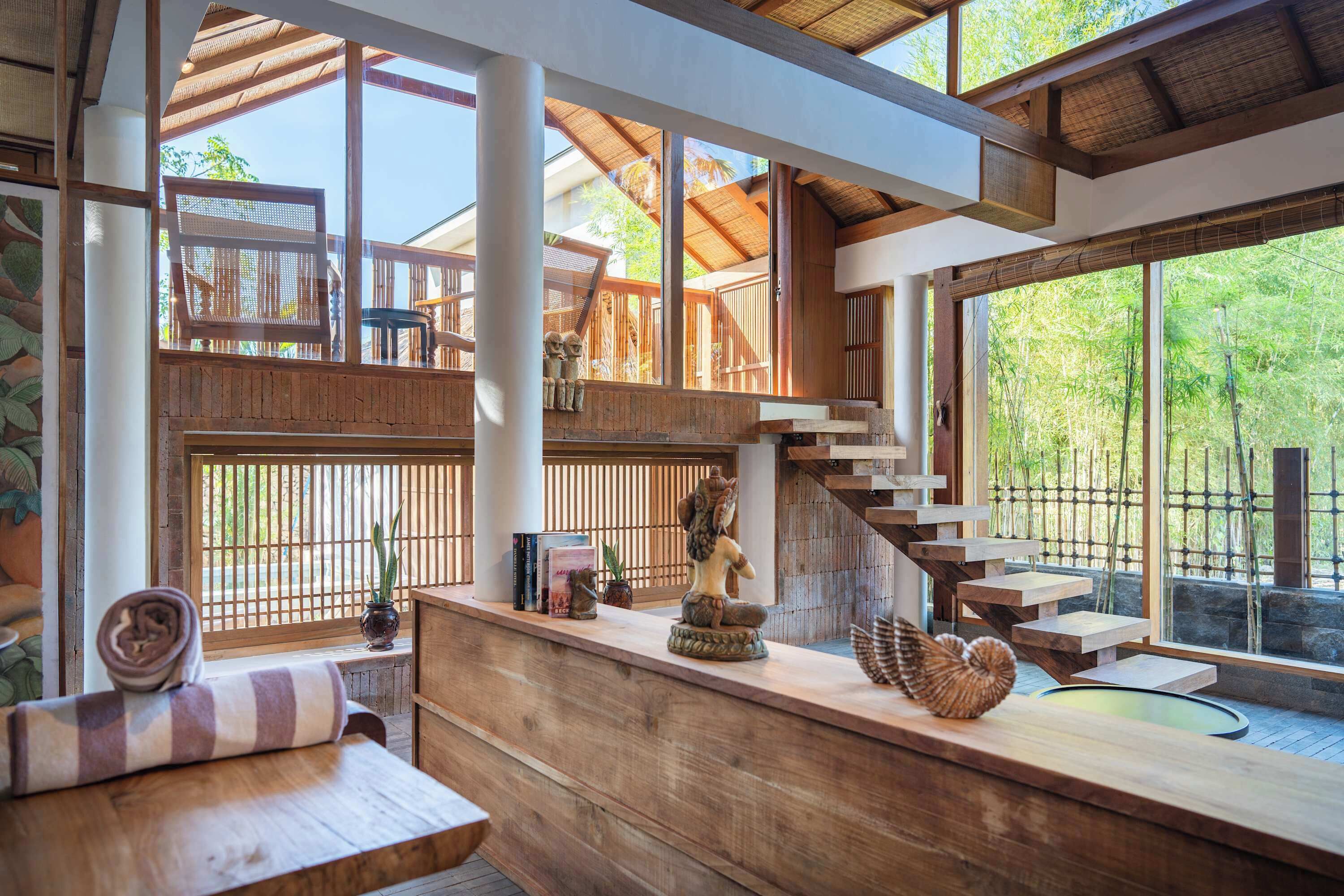 A wooden interior with a staircase, a bench, and a statue.