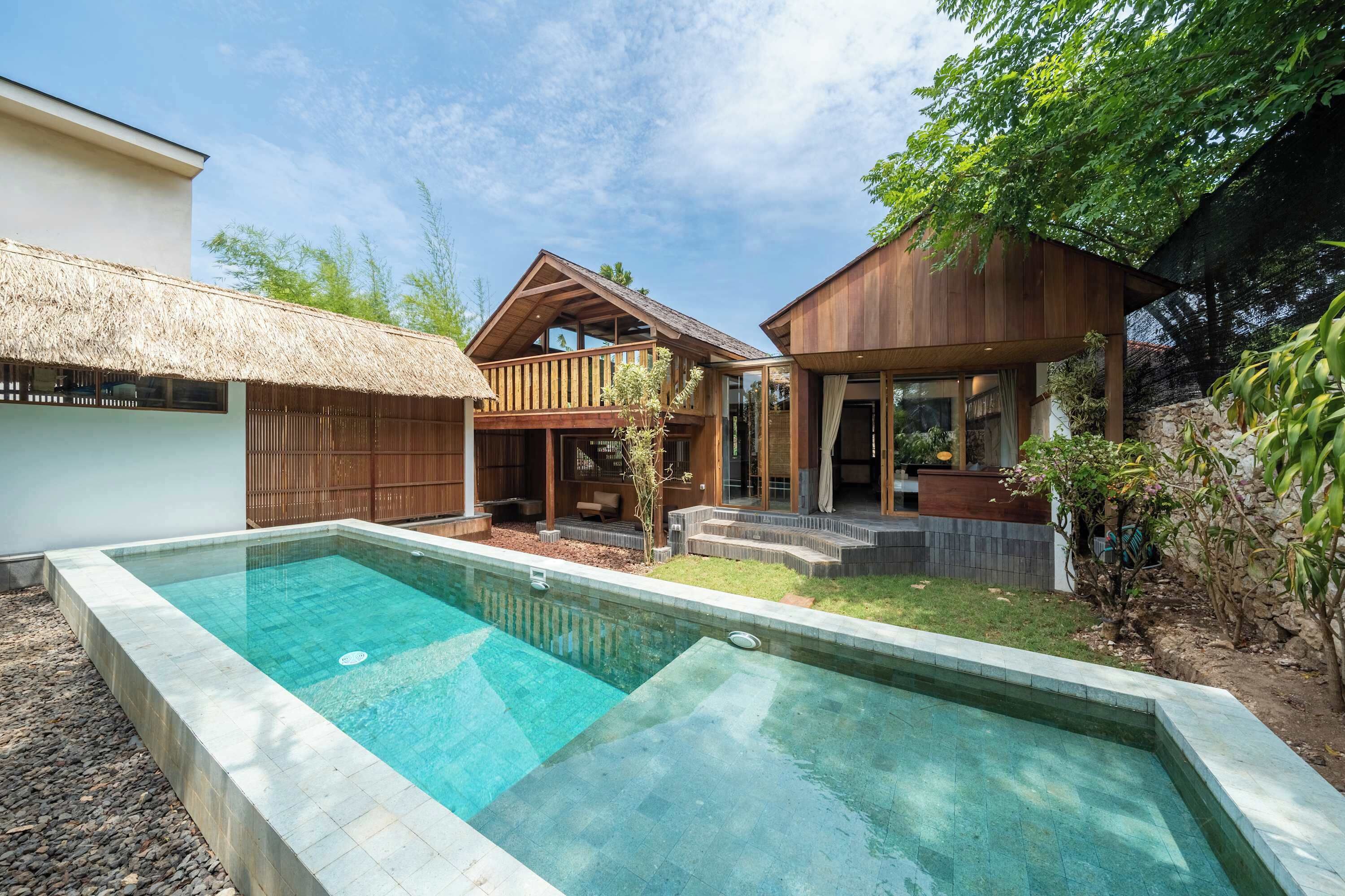 A modern house with a swimming pool, wooden deck, and a thatched roof structure.