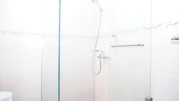 A glass-enclosed shower area with a handheld showerhead, a towel rack, and a glass partition.