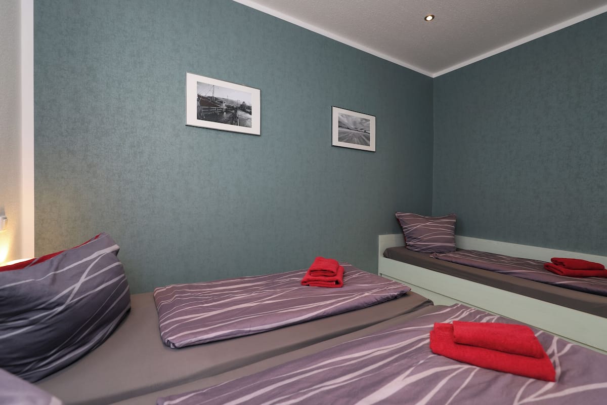 Une chambre avec deux lits, chacun étant équipé d’un oreiller et d’une serviette rouge pliée.