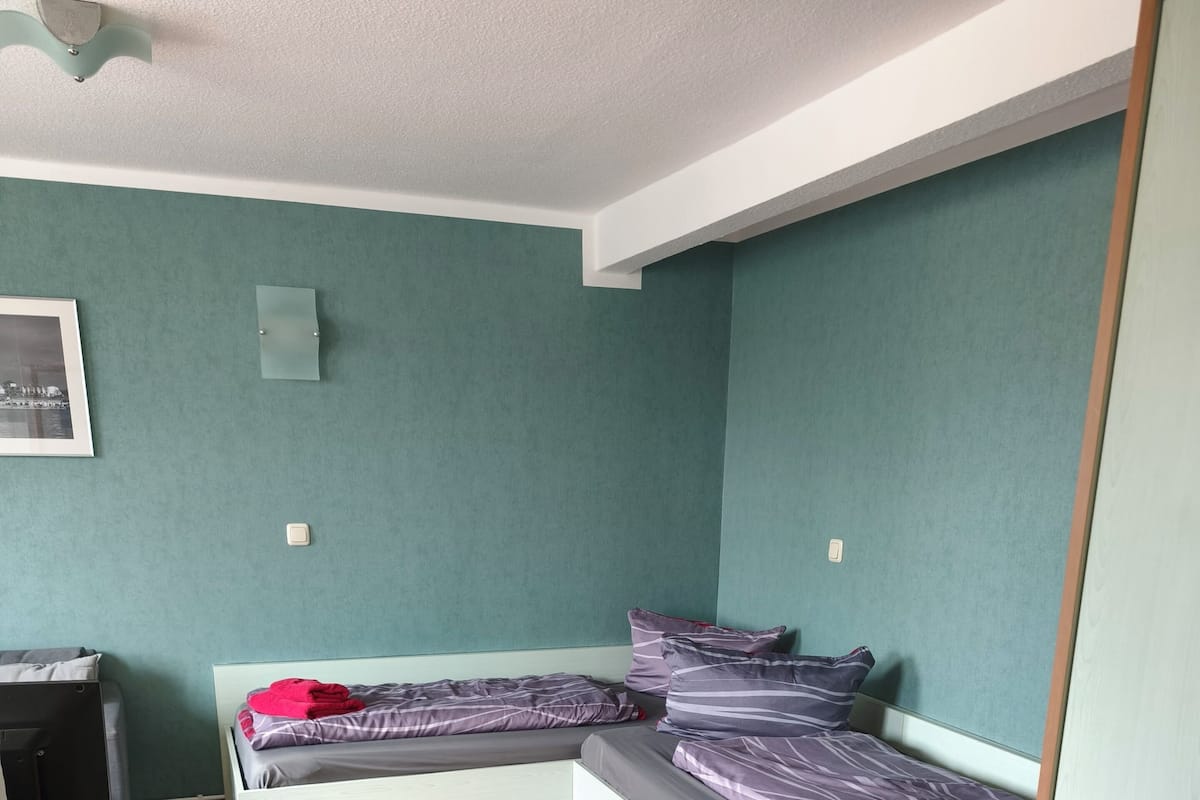 Une chambre avec un lit, un bureau et un ventilateur de plafond.