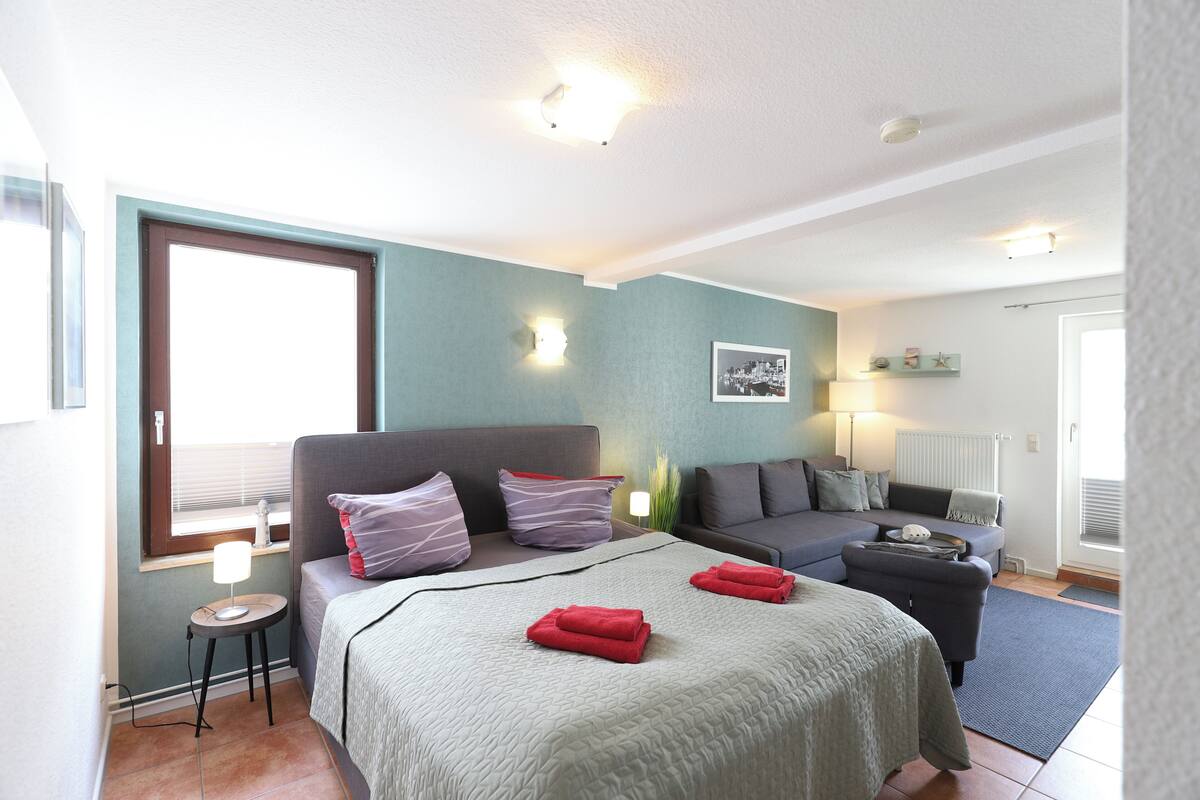 Une chambre à coucher avec un lit, un canapé, une petite table et une table de chevet.