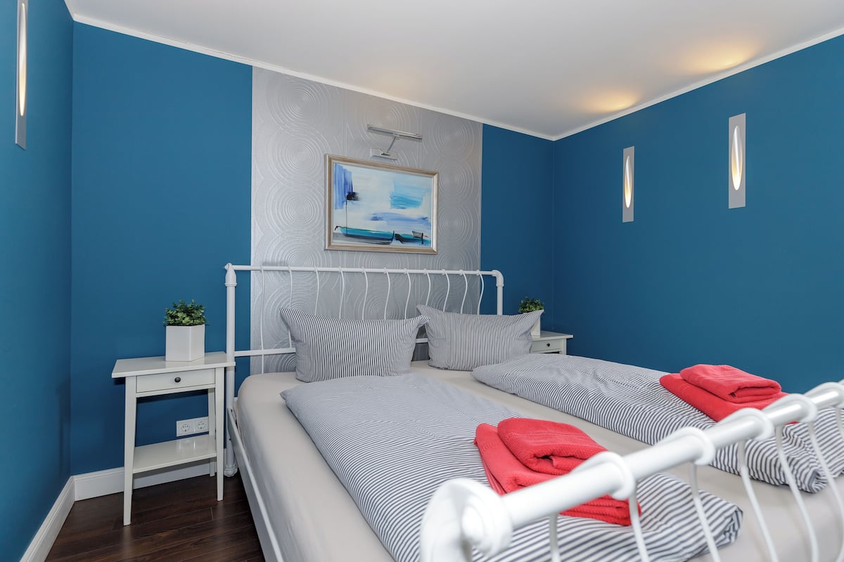 Une chambre à coucher avec un lit, des tables de chevet, un tableau et un mur bleu.