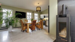 Una cocina moderna con estufa integrada, una zona de comedor con muebles de madera y una planta grande en maceta.