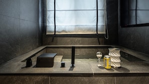 A modern bathroom with a bathtub, a towel rack, a glass of water, and a can of soda. - Cave Ryokan Hotel by Anook Daejeon Yucheon Southwest Terminal (Daejeon)