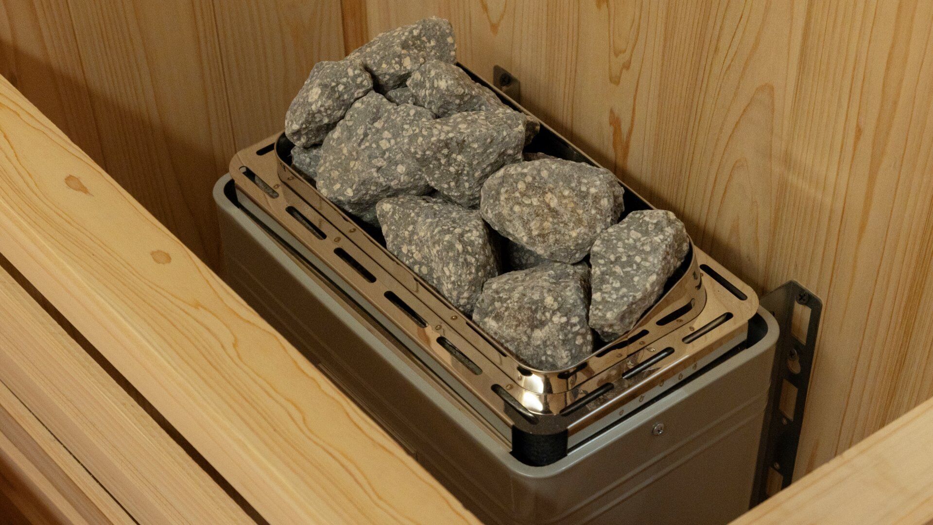 Un módulo metálico con interior de madera, que contiene una cesta de piedras.