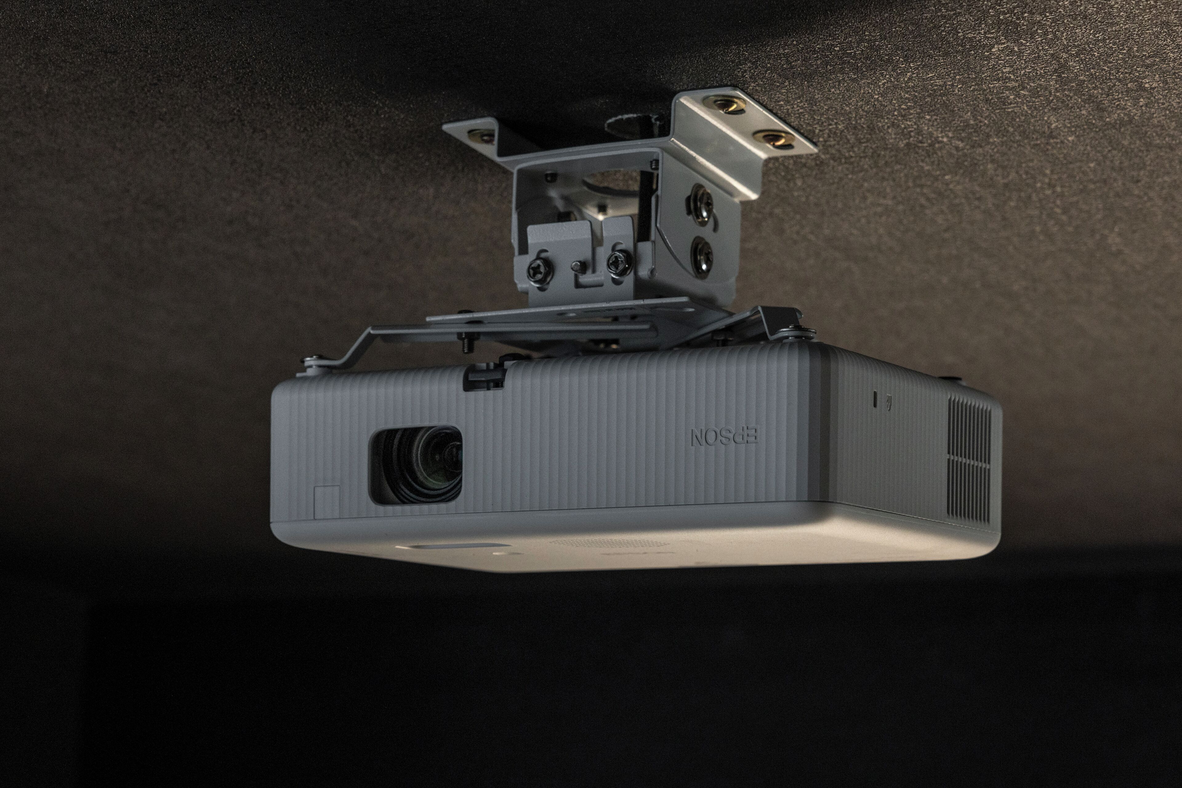 Proyector montado en el techo, con lente y rejillas de ventilación.