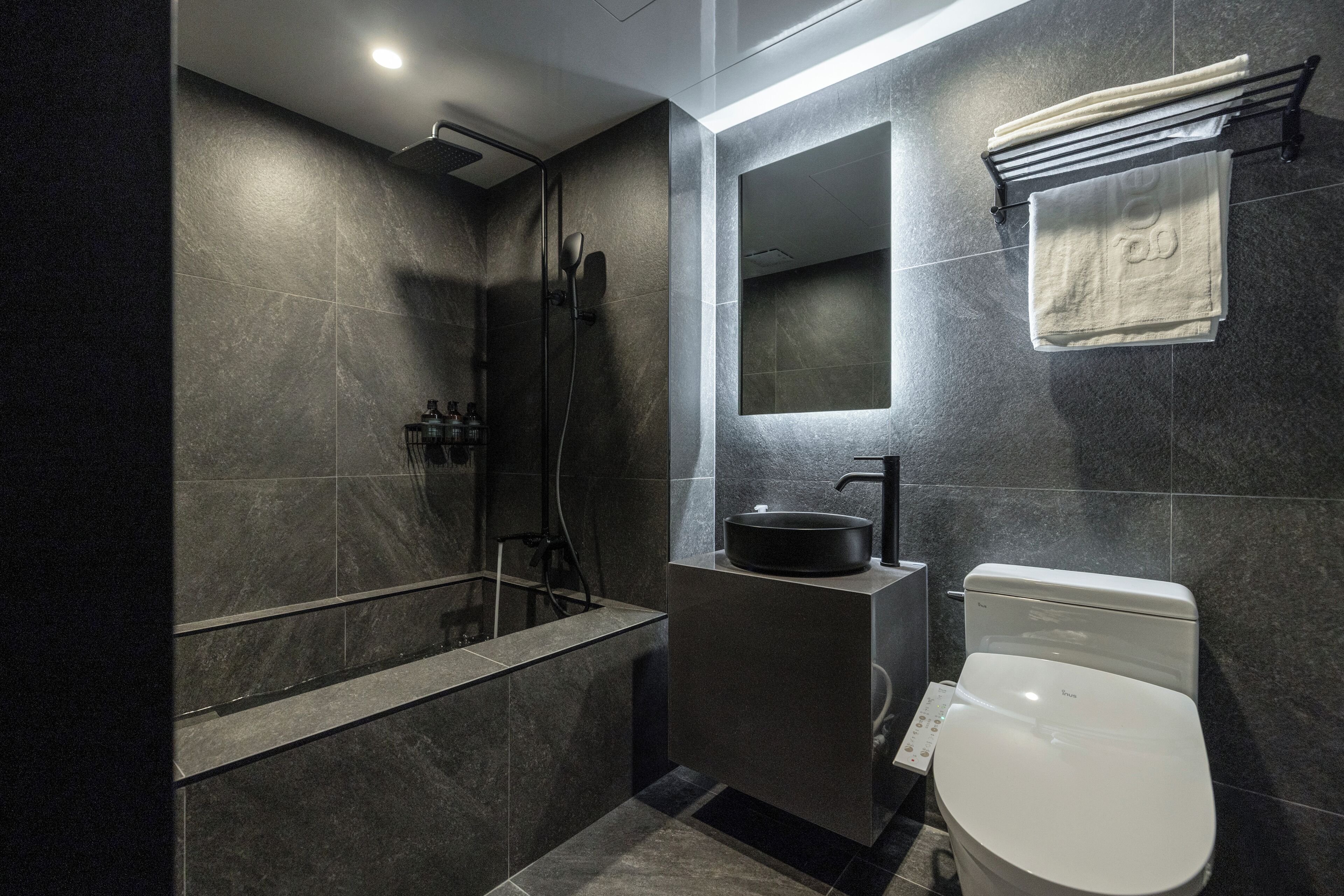 Un baño moderno con ducha, inodoro, lavabo y un perchero para toallas.