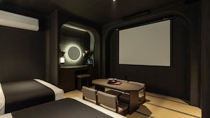 A modern hotel room with a bed, a small table with chairs, a desk with a computer, a mirror, and a projector screen. - Cave Ryokan Hotel by Anook Daejeon Yucheon Southwest Terminal (Daejeon)