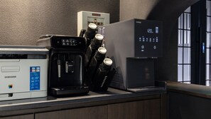 A coffee machine, a refrigerator, and a digital display on a counter.