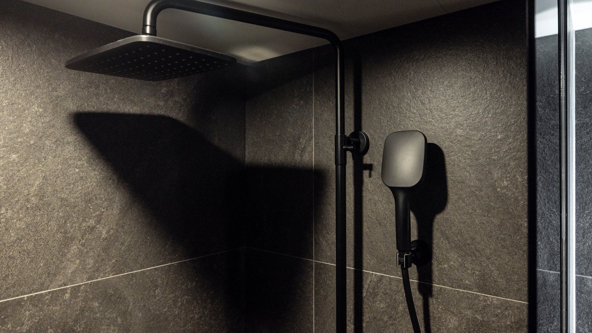 Eine moderne Dusche mit Handbrause und einer fest installierten Bedienblende.