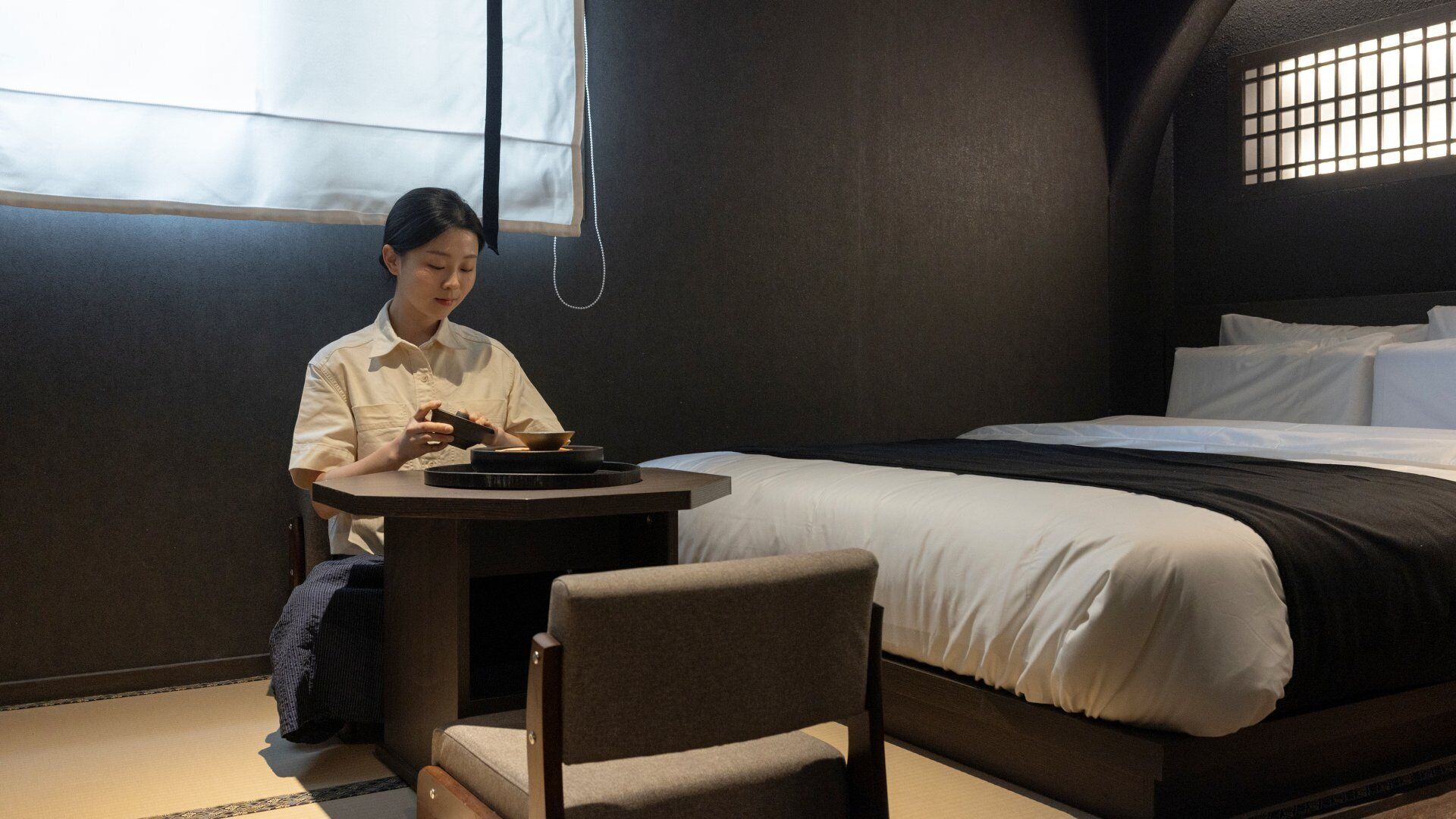 A hotel room with a bed, a small round table, and a chair.