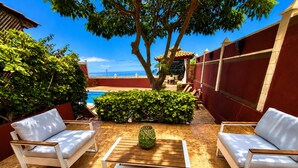 A poolside area with white outdoor furniture, a wooden table, and a view of the sea. - Villa Zen Adeje - Private Heated Pool (Adeje)