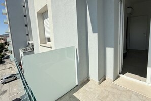 Un edificio moderno con un balcone, una porta in vetro e vista sulla zona circostante.