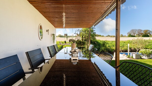 A covered outdoor dining area with a long table, chairs, and a view of the countryside. - Apartment 'Haus Am Idyllischen Bach' with Private Garden and Wi-Fi (Rheinau)
