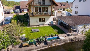 A two-story house with a balcony, a small garden, and a canal in front. - Apartment 'Haus Am Idyllischen Bach' with Private Garden and Wi-Fi (Rheinau)