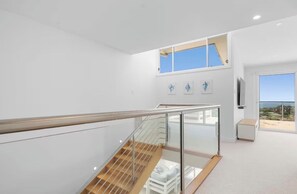 A modern interior with a glass railing staircase, a large window with a view, and a minimalist design. - AcquaVista (Terrigal)