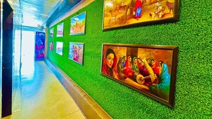 Un pasillo con paredes de césped artificial verde, obras de arte enmarcadas y suelo de baldosas.