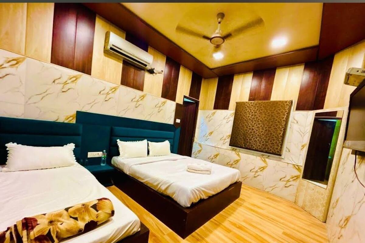 Habitación de hotel con dos camas, ventilador de techo, aire acondicionado y papel tapiz estampado.