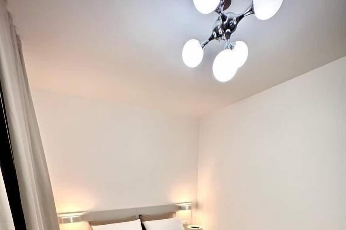 A bedroom with a bed, bedside tables, a lamp, and a ceiling light fixture.