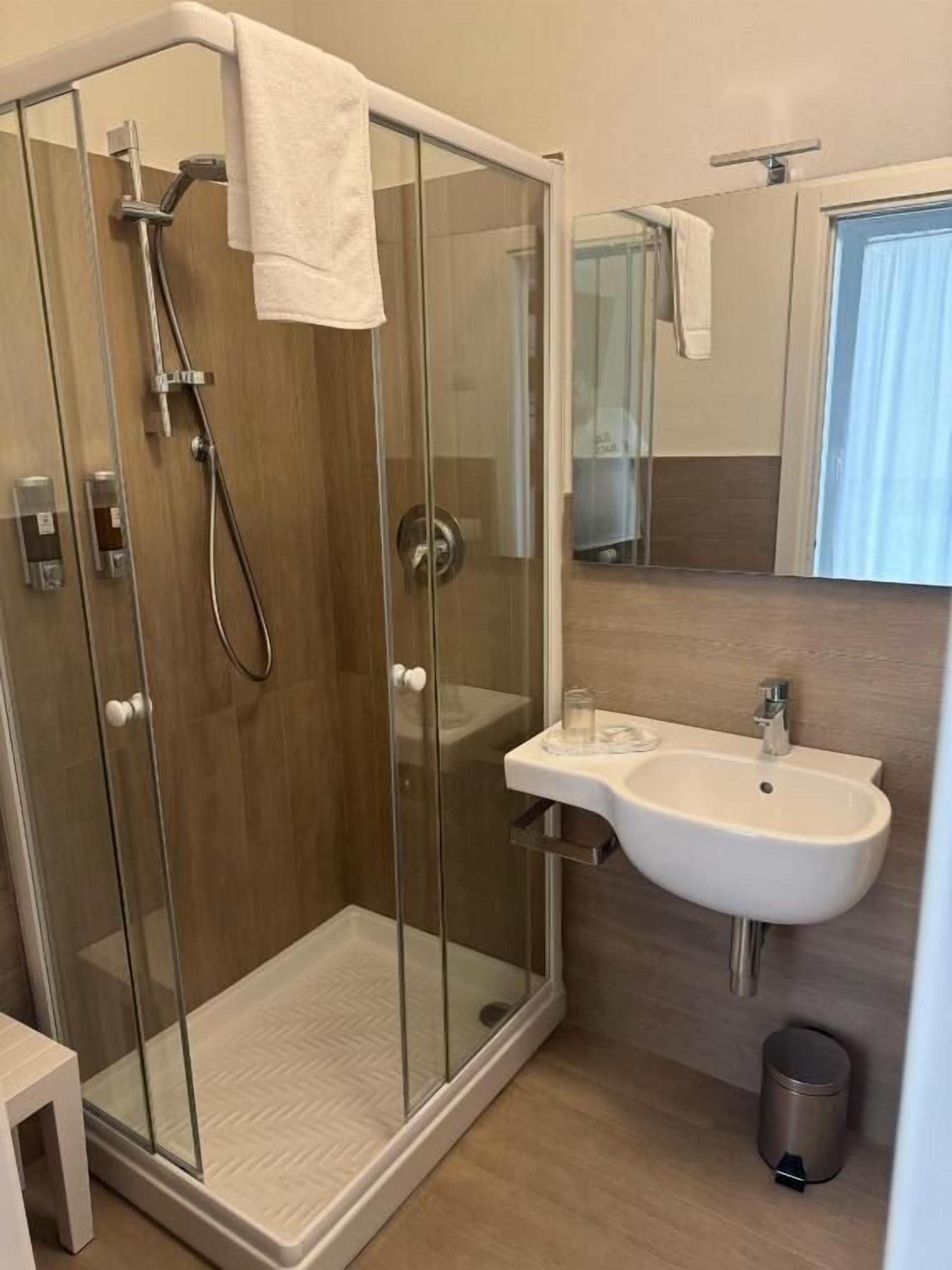 A modern bathroom with a glass-enclosed shower, a sink, and a mirror.