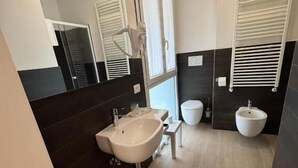 A modern bathroom with a large mirror, a sink, a toilet, and a bidet. - HOTEL VILLA MARY (Santa Maria di Sala)