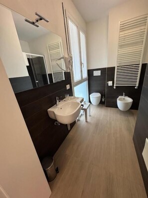 Un bagno moderno con uno specchio grande, un lavandino, un water e un bidet.