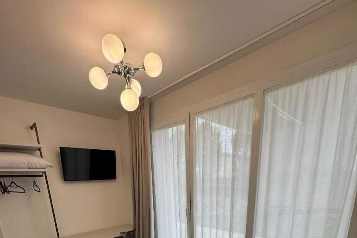 A hotel room with a bed, a desk, a TV, and a wardrobe.