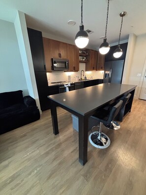 A modern kitchen with a central island, dark cabinetry, and pendant lighting. - Cozy contemporary & chic Deep Ellum apartment in Dallas’s nightlife district (Dallas)