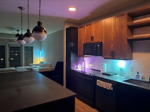 A modern kitchen with wooden cabinets, a microwave, and a glass island. - Cozy contemporary & chic Deep Ellum apartment in Dallas’s nightlife district (Dallas)