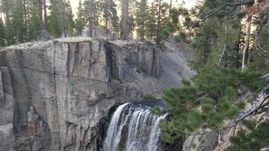 Una cascada que se precipita por un risco rocoso rodeado de árboles.