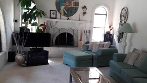 Una sala de estar con chimenea, sofás, una mesa de centro y un televisor.