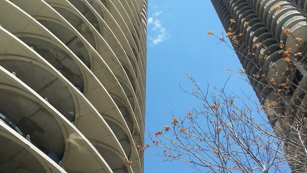 Un edificio alto con fachada curva y un cielo azul despejado al fondo.