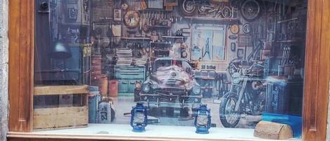 A window display with a vintage car, lanterns, and various mechanical parts.