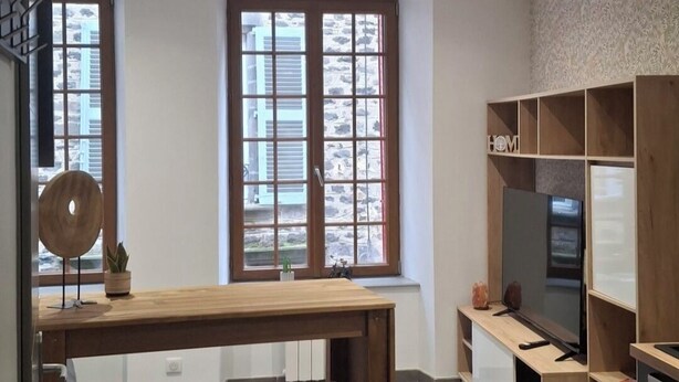 Een moderne keuken met een houten kookeiland, twee barkrukken, een televisie en inbouwkasten.