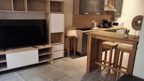 Een moderne keuken met een ingebouwde televisie, houten barkrukken en een eethoek.