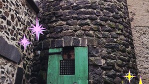 Een stenen toren met een klein raam en een groene deur onderaan.