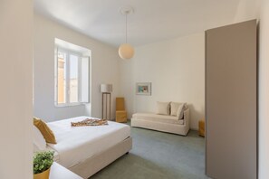 Un dormitorio con cama, sofá, lámpara de pie y un cuadro en la pared.