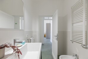 A modern bathroom with a large bathtub, a sink, and a mirror. - iFlat | Calm & Spacious Urban Oasis Fons Trevi B13 (Rome)