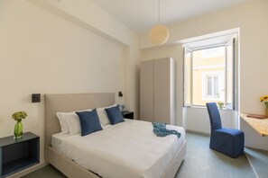 A bedroom with a bed, bedside table, chair, wardrobe, and a window with a view. - iFlat | Calm & Spacious Urban Oasis Fons Trevi B13 (Rome)
