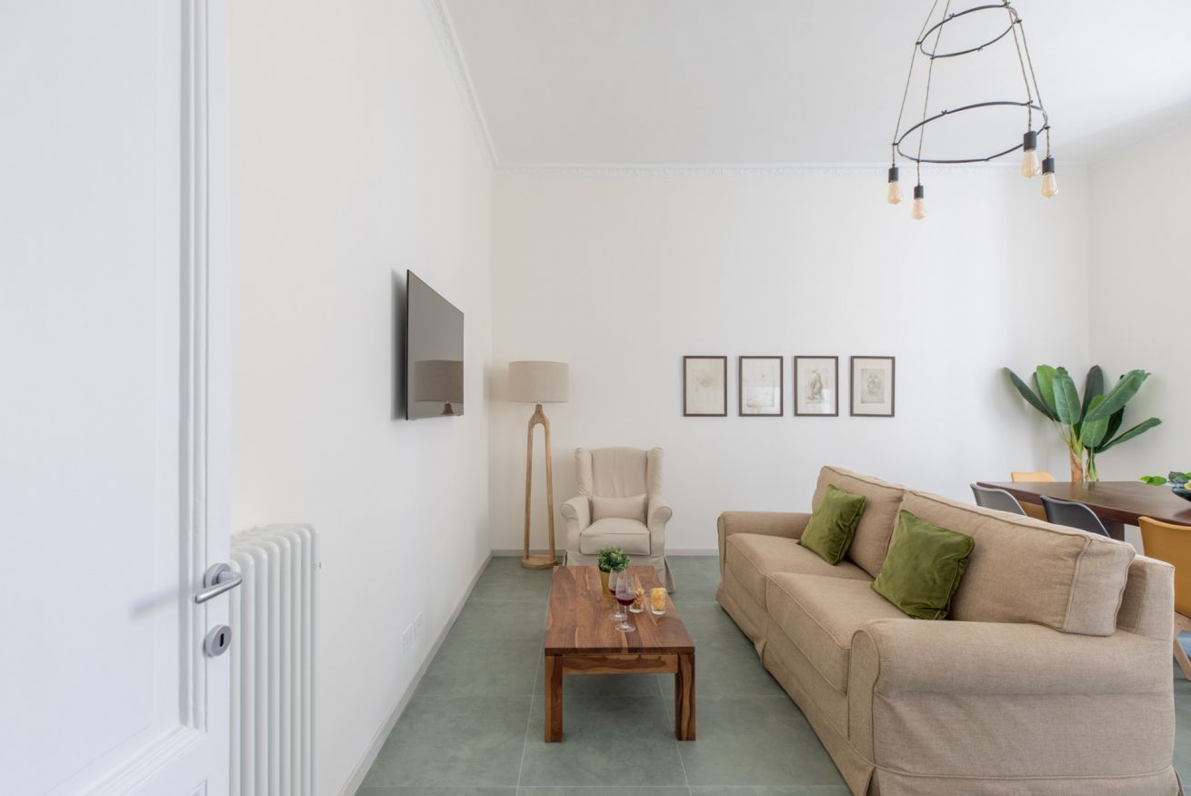 A living room with a sofa, coffee table, lamp, and framed pictures on the wall.