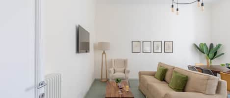 Una sala de estar con sofá, mesa de centro, lámpara y cuadros en la pared.