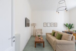 A living room with a sofa, coffee table, lamp, and framed pictures on the wall. - iFlat | Calm & Spacious Urban Oasis Fons Trevi B13 (Rome)