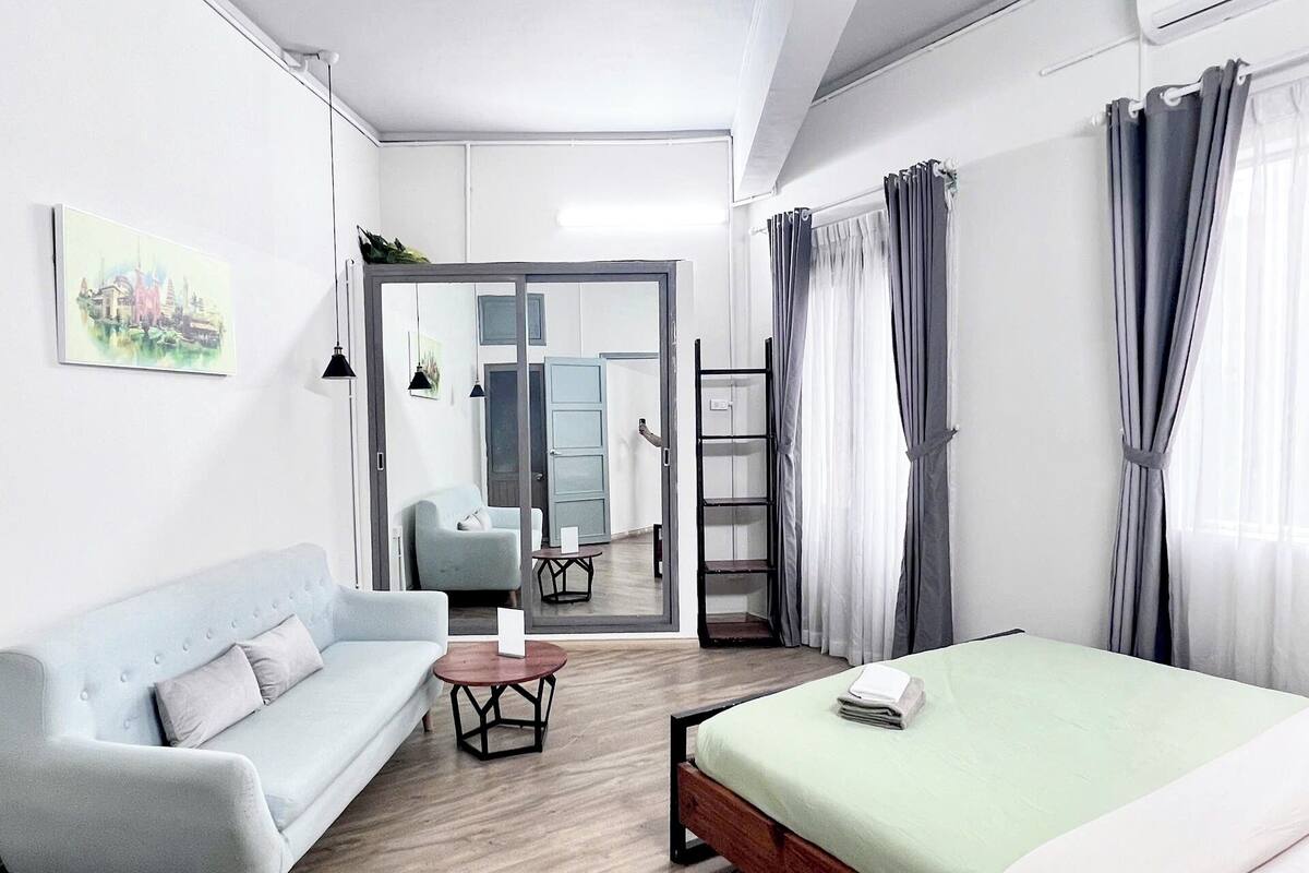 Ein modernes Hotelzimmer mit einem Bett, einer Couch, einem kleinen Tisch und einem Spiegel.